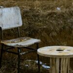 Zardzewiałe metalowe krzesło i biały stolik na trawie na wsi