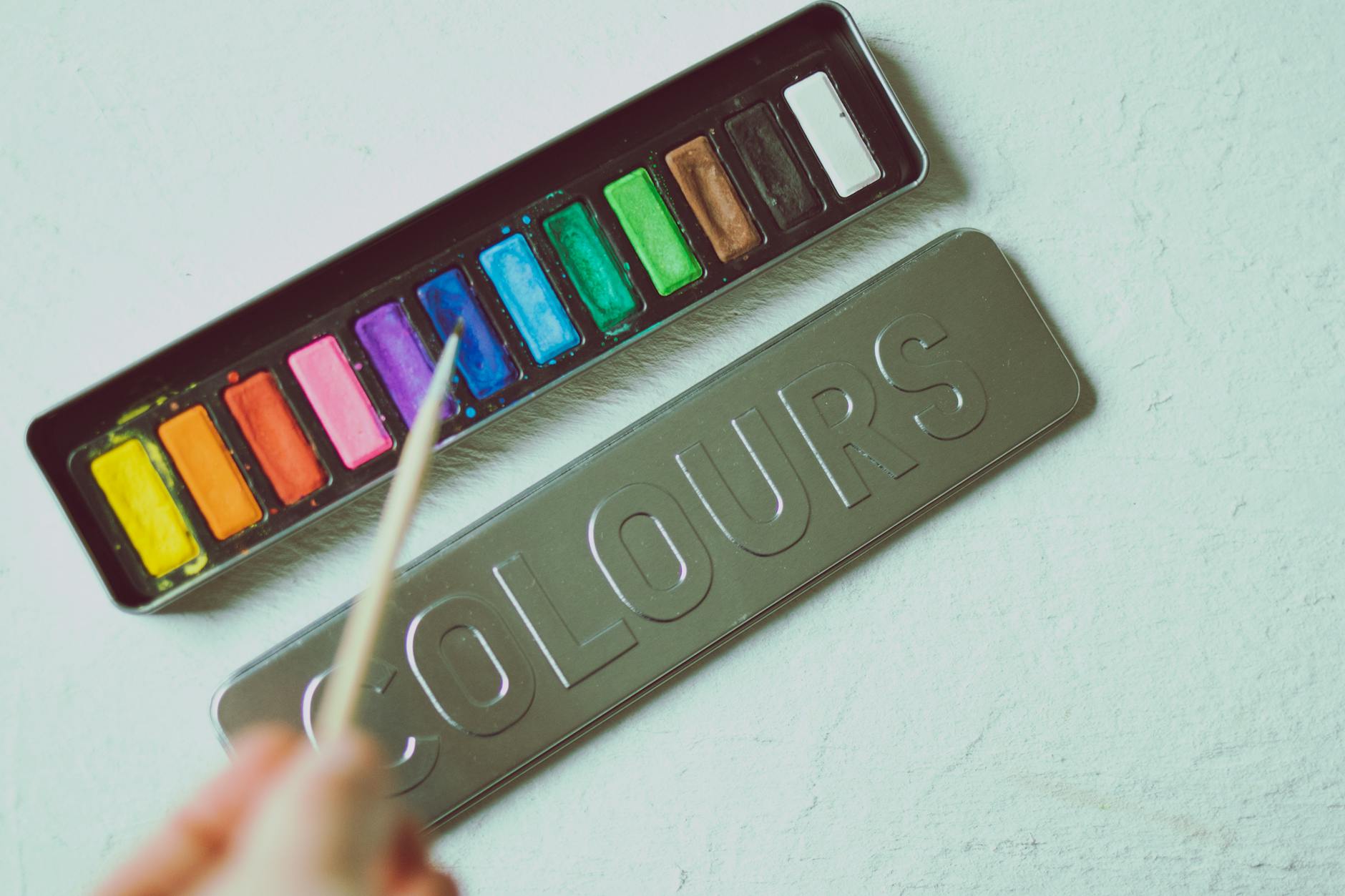 Kolorowa paleta akwareli i pędzel na jasnym blacie