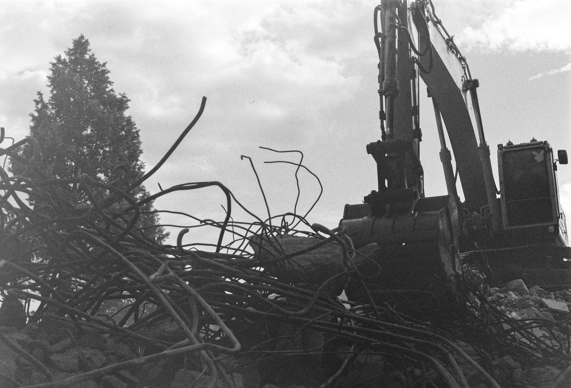 Koparka burząca budynek wśród gruzów podczas rozbiórki