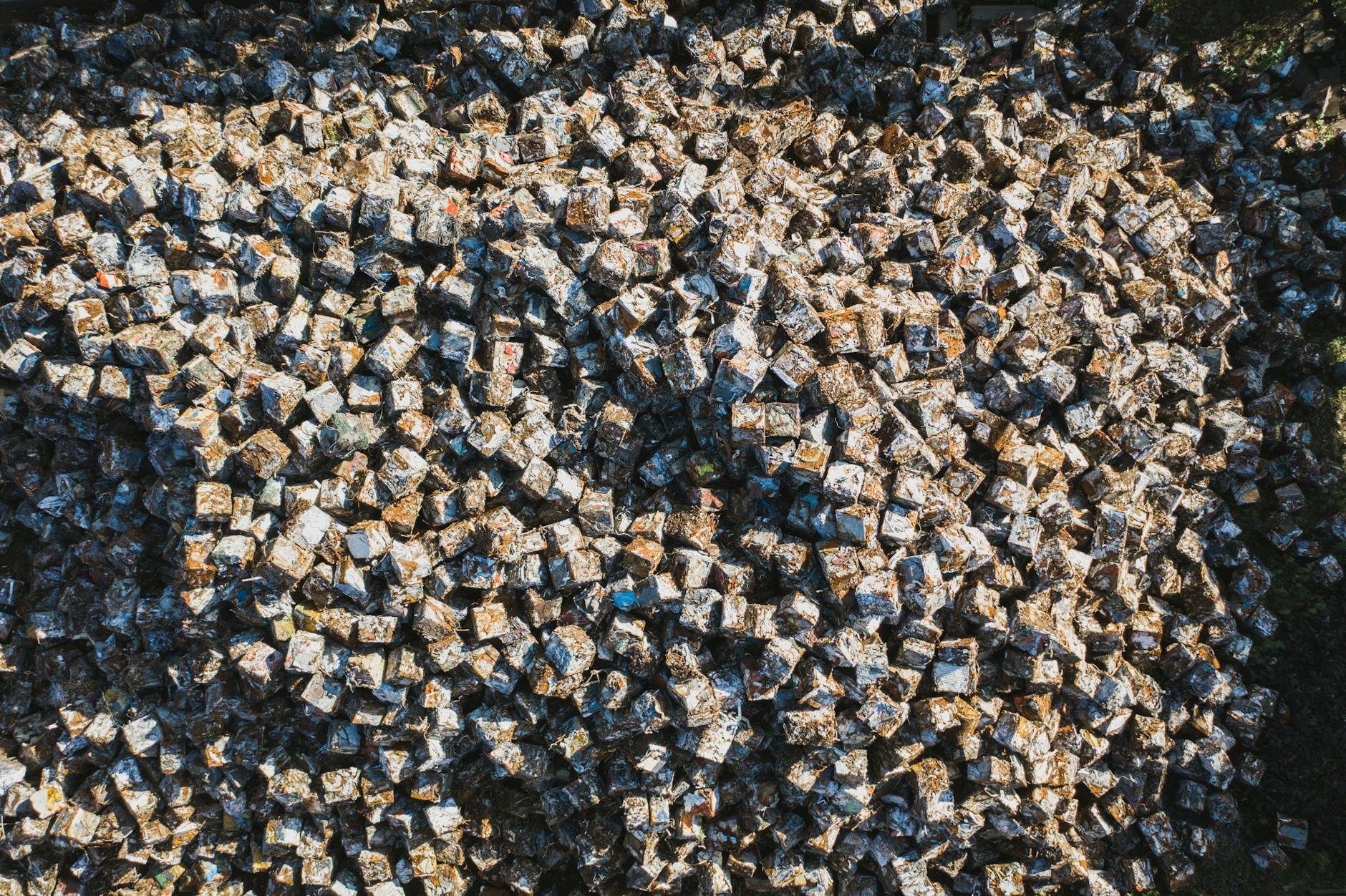 Sześciany złomu metalowego ułożone gęsto na skupie recyclingu