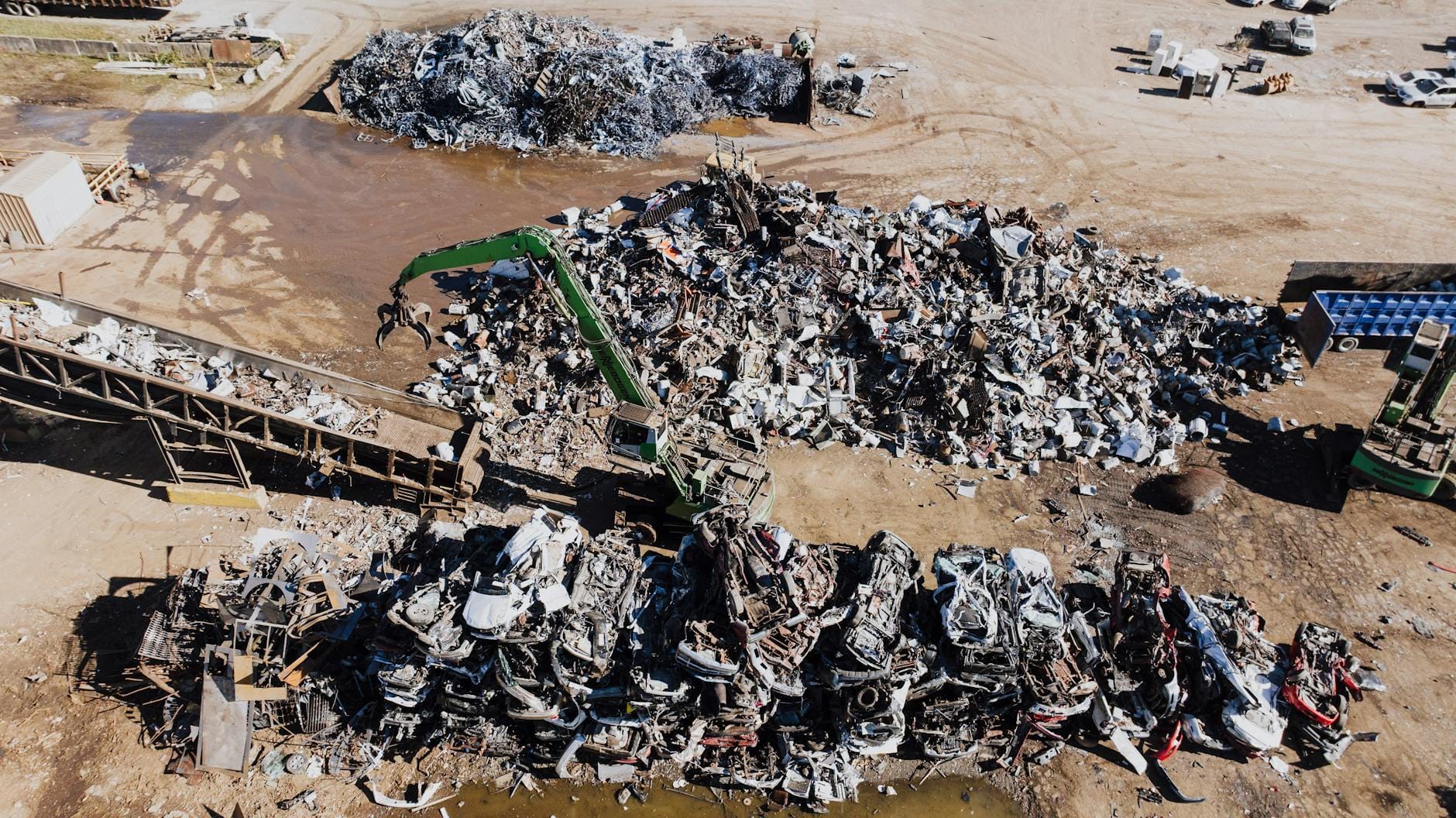 Złomowisko z hałdami metalu i koparką chwytakową na placu przemysłowym