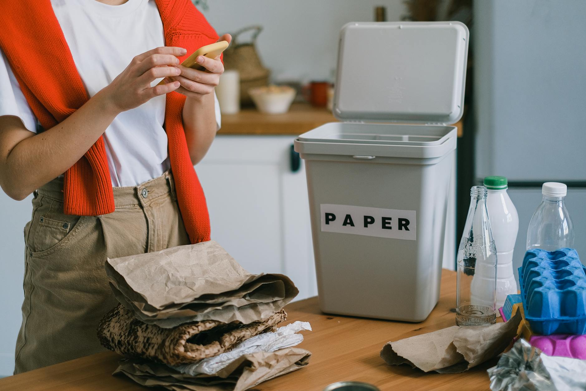Segregacja papieru w kuchni, osoba wrzuca odpady do pojemnika na papier