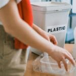 Kobieta segregująca plastikowe odpady do pojemnika w jasnym mieszkaniu