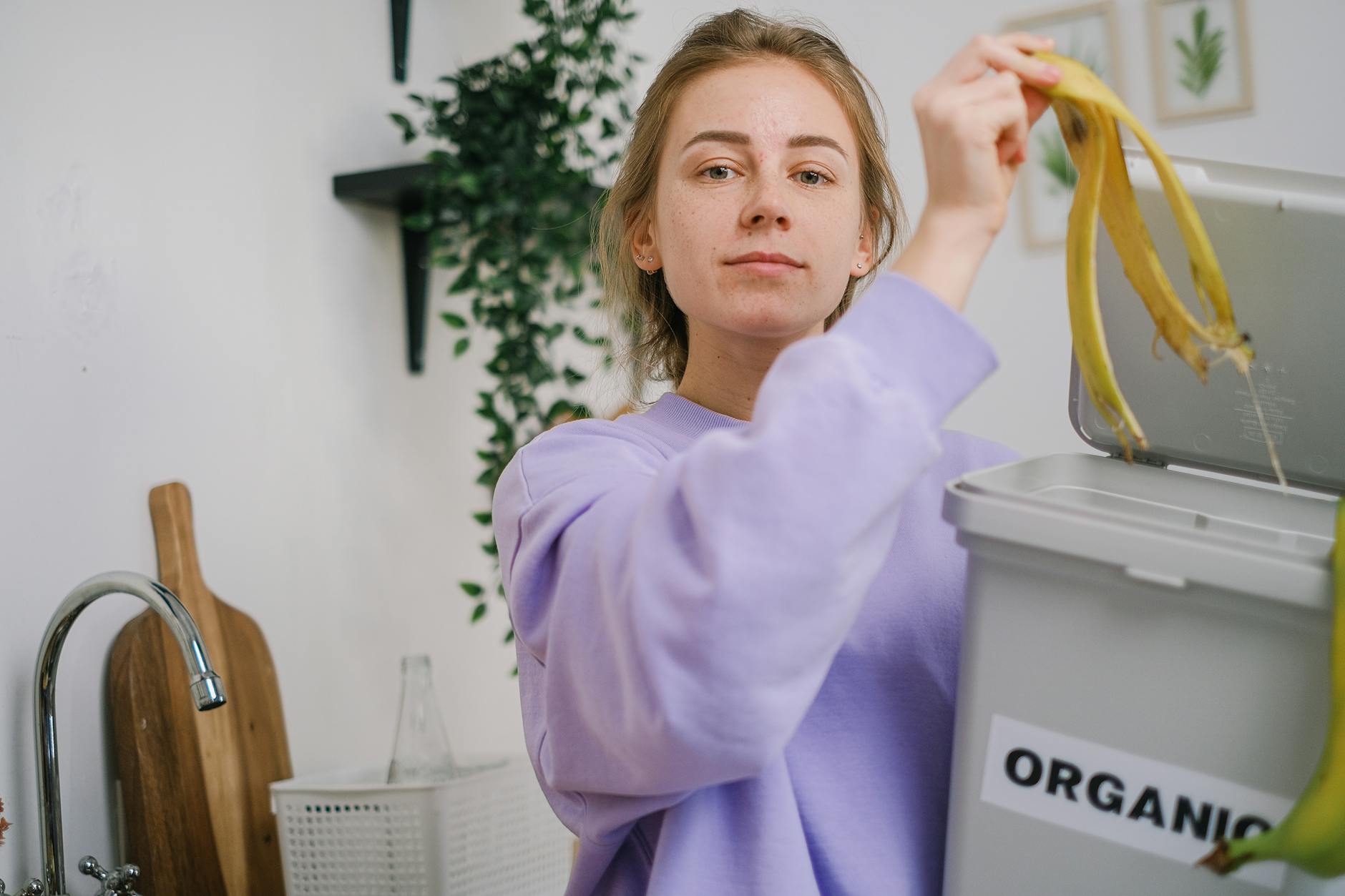 Kobieta wrzuca skórkę banana do domowego pojemnika na bioodpady