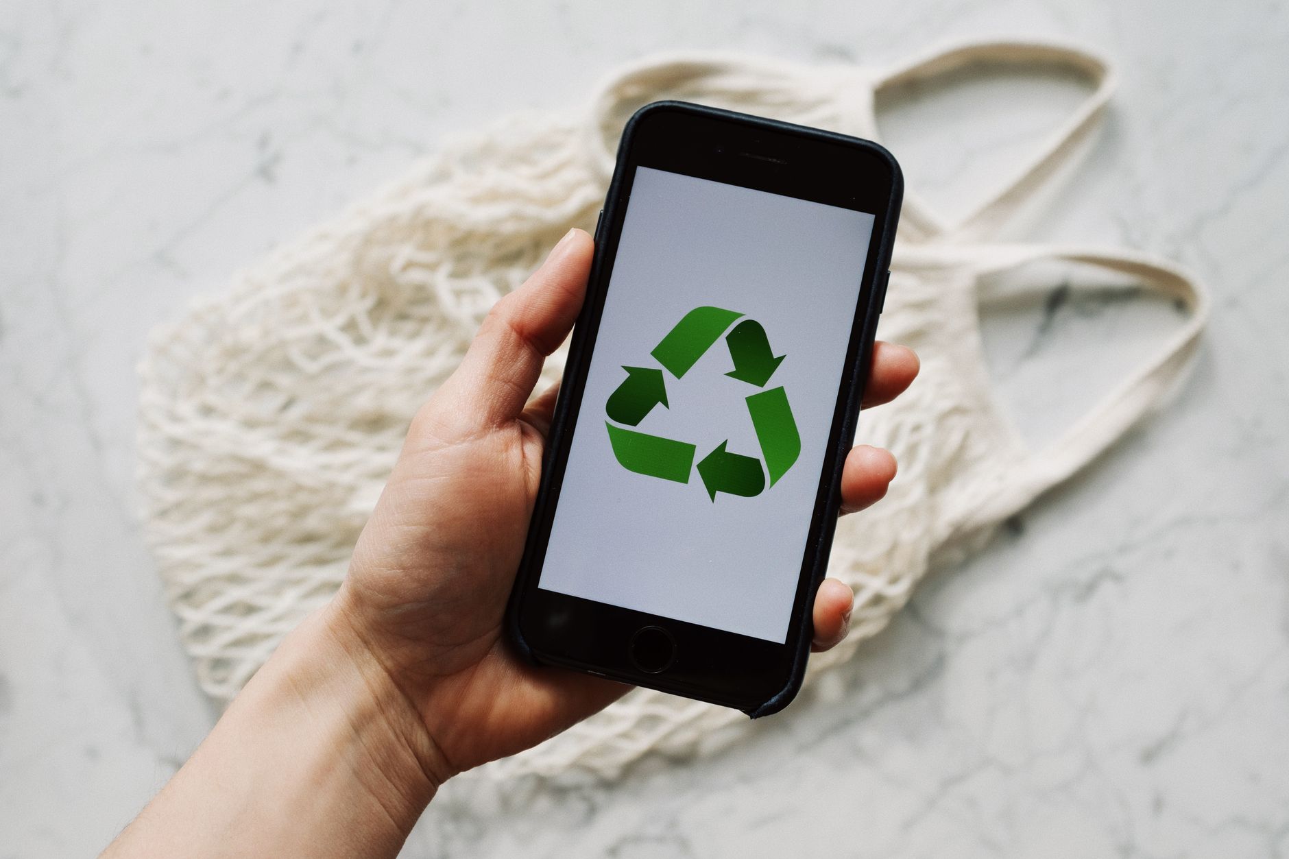 Dłoń trzymająca smartfon z symbolem recyklingu na ekranie