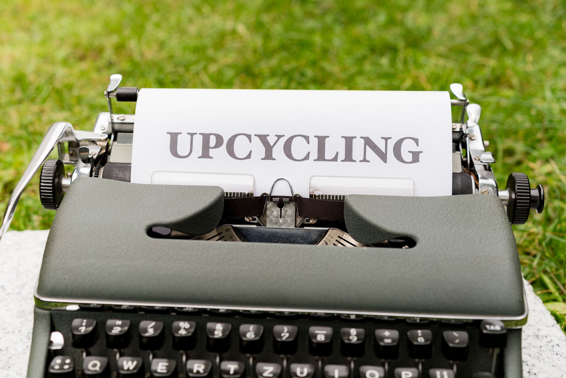 Retro maszyna do pisania z napisem upcycling na trawie
