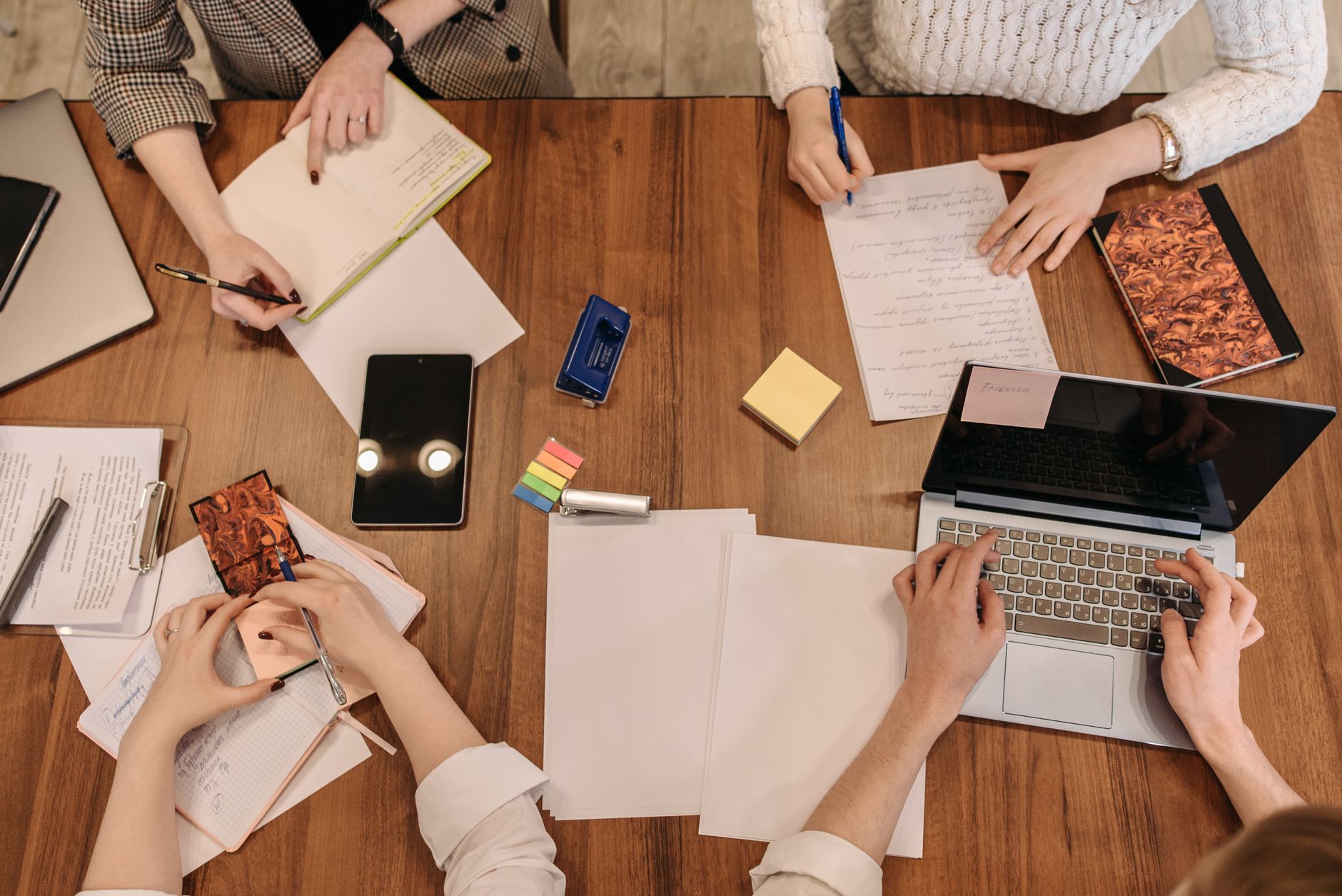 Zespół w biurze planuje projekt IT przy laptopach i notatnikach